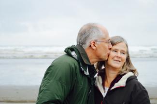 man kissing woman on check beside body of water by Esther Ann courtesy of Unsplash.