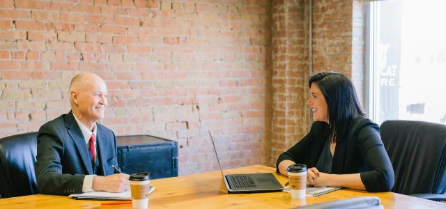 man and woman talking inside office by Amy Hirschi courtesy of Unsplash.